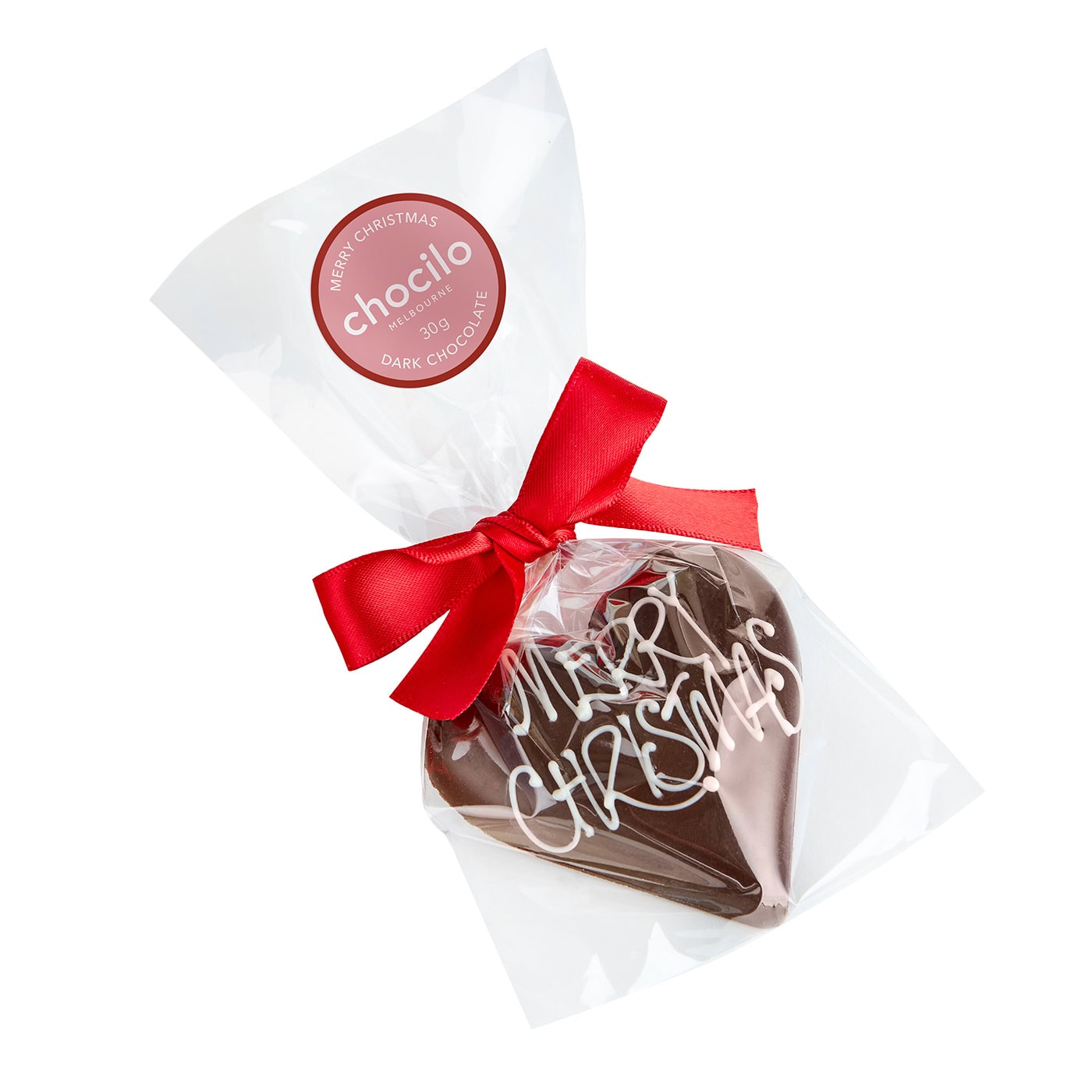 A heart-shaped dark chocolate filled with smooth hazelnut praline, decorated with white icing that reads 'MERRY CHRISTMAS', individually wrapped in clear cellophane with a red ribbon.