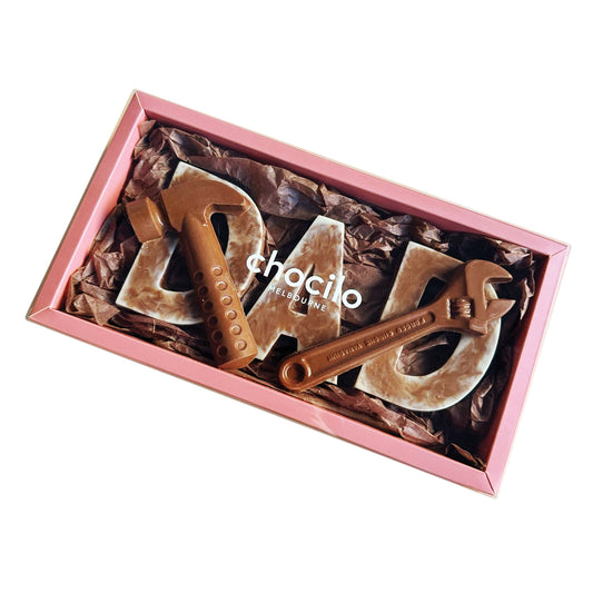 Chocolate shaped like tools in a pink box with 'Chocilo' branding with D.A.D milk and white chocolate letters.